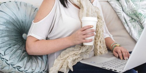 content creator holding coffee cup as she reviews news stories that affect her customers