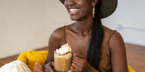 smiling content creator holding cup of coffee during live stream with curated content for customer segment